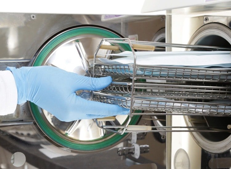 Package integrity testing services. Sterilizing tools. Technician in gloves putting bags in sterilizer