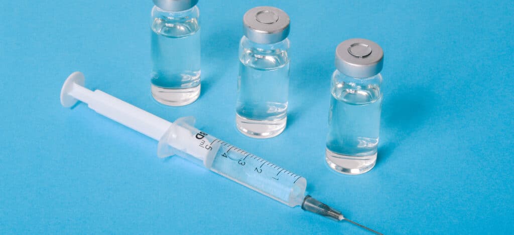 Picture of three vials and a syringe on a light blue background. How does the FDA classify medical devices. FDA classifications for medical devices. Regulatory controls for medical devices. Premarket approval submission for FDA marketing. FDA product classification. How to determine FDA classification for medical devices