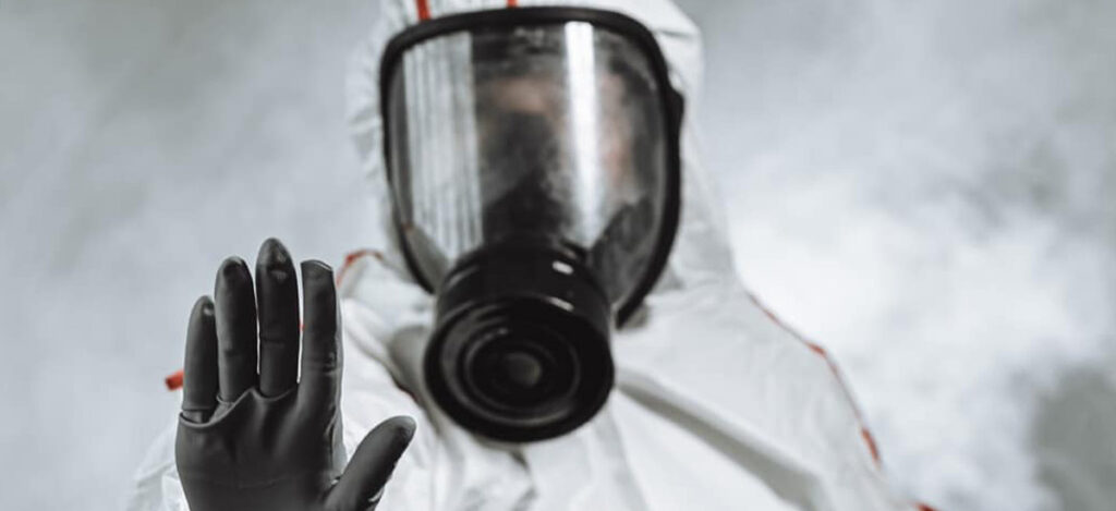 Picture of a man with a gas mask and a protective suit for sterilization